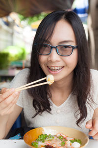 Close-up portrait of smiling young woman eating food