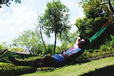 Man lying down on grass against trees