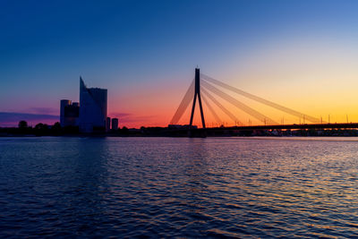 Suspension bridge over river against sky during sunset