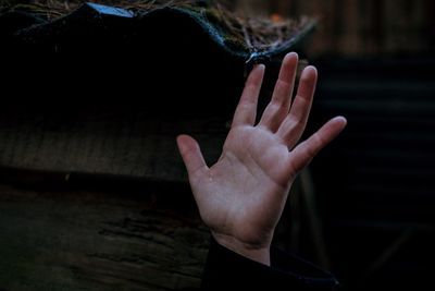 Cropped hand touching wet roof during rainy season