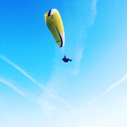 Low angle view of paragliding against clear blue sky