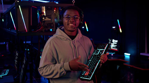 Portrait of young man standing in internet cafe