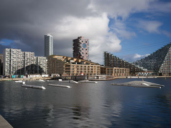 Buildings by river against sky