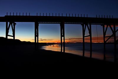 Silhouette pier over sea against sky during sunset