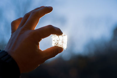 Close-up of hand holding ice cream against sky