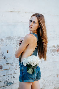 Beautiful young woman standing against wall