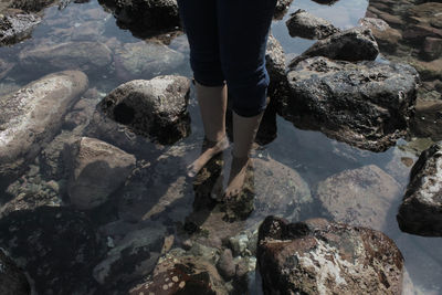 Low section of person standing on rock at beach