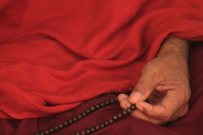 Midsection of monk holding prayer beads