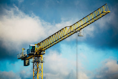 Construction crane against cloudy blue sky.