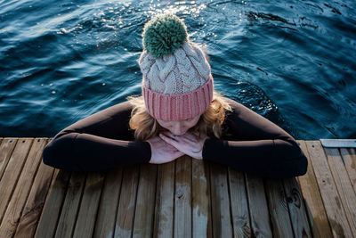 Woman leaning on a pier whilst swimming in cold ice water in winter