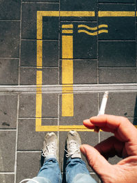 Low section of man smoking cigarette on footpath