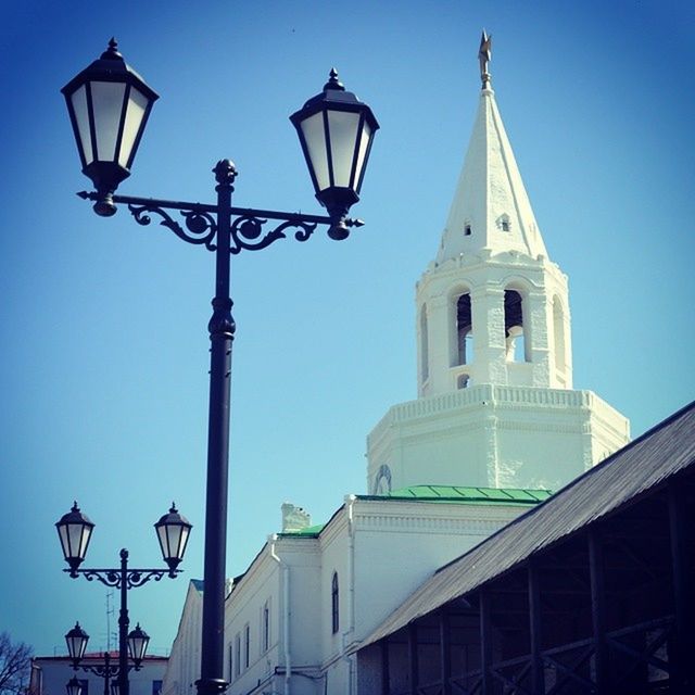 low angle view, architecture, built structure, building exterior, church, religion, place of worship, clear sky, spirituality, street light, blue, cross, lighting equipment, dome, sky, high section, tower, lamp post