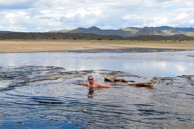Full length of shirtless man swimming at the hot springs of lake magadi, kenya 