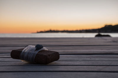 Close-up of pier over sea against sky during sunset