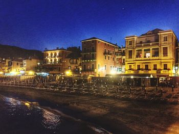 Illuminated buildings against blue sky at night