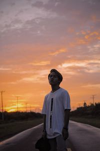 Full length of man standing on road against sky during sunset