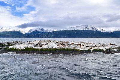 Scenic view of sea by mountains against sky