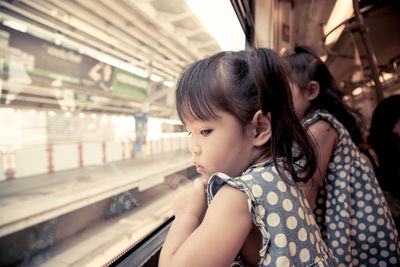 Close-up of girls in train looking through window