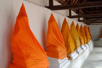 Statues covered with orange fabrics in buddhist temple