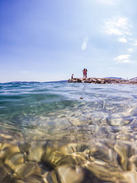 People in sea against sky