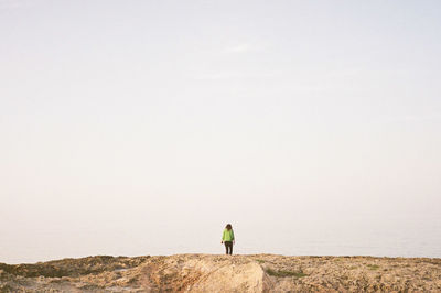 Rear view of man standing on land against sky