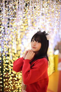 Portrait of young woman standing against christmas tree