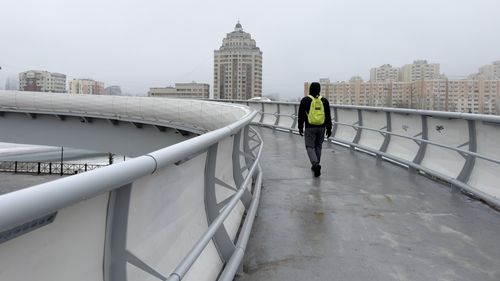 Rear view of man walking on bridge