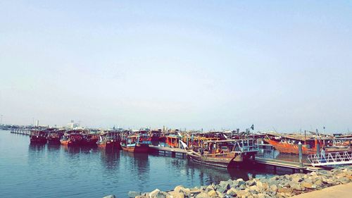 Boats moored at harbor against clear sky