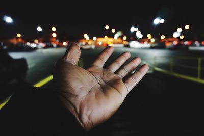 Cropped image of hand on illuminated road at night