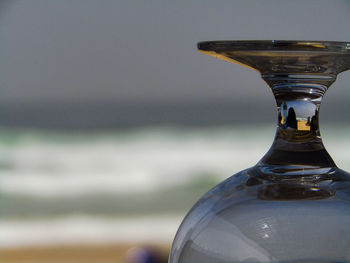 Close-up of glass bottle against sea