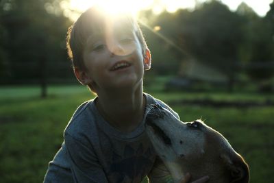 Portrait of smiling boy with dog on field