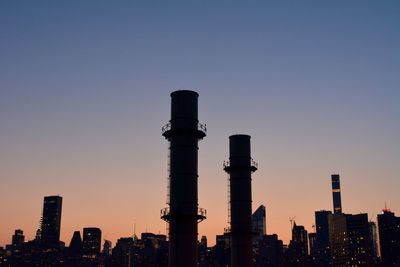 Buildings in city against clear sky during sunset