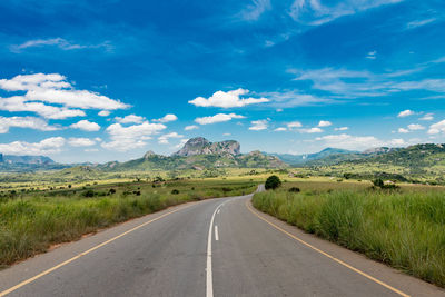 Road amidst field against sky