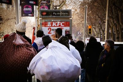 Rear view of people walking on street in city