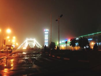 Illuminated city street against sky at night