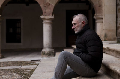 Adult man sitting on stair of town square of siguenza, castilla la mancha, spain