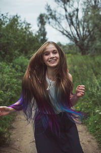 Portrait of smiling young woman standing against trees