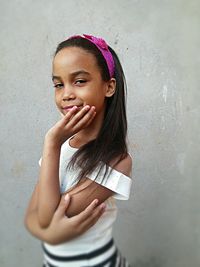 Portrait of girl standing against wall