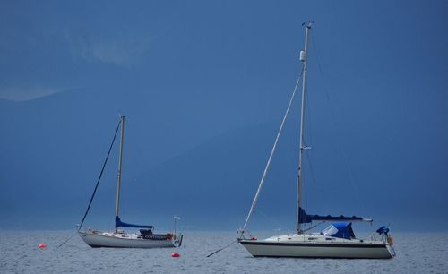 Boats sailing in sea against blue sky