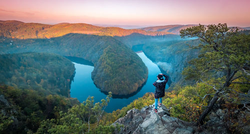 Rear view of man standing against mountains and river