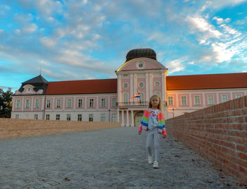 Woman standing by building against sky