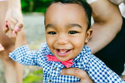 Closeup cropped portrait of a smiling baby boy in a bow tie outdoors