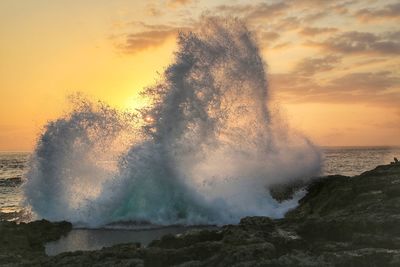 Sea waves splashing on rocks during sunset