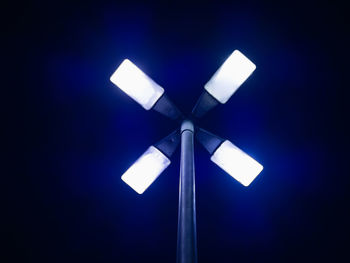 Low angle view of illuminated lamp against blue sky