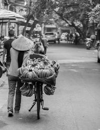 Rear view of people walking on sidewalk in city