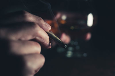 Close-up of man smoking cigarette against black background