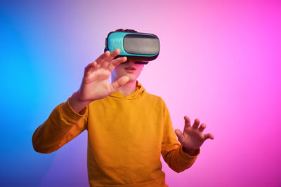 Boy with virtual reality glasses on the colorful background. future technology, vr concept