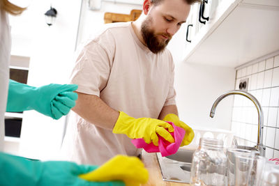 Bearded man cleaning utensils with woman at home