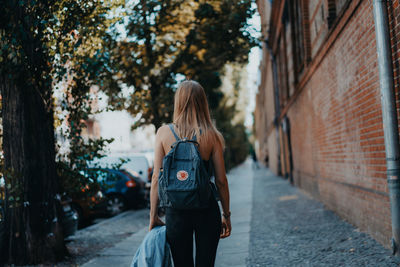 Rear view of woman walking on footpath in city