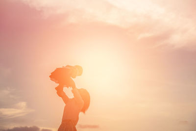 Side view of silhouette woman standing against sky during sunset
